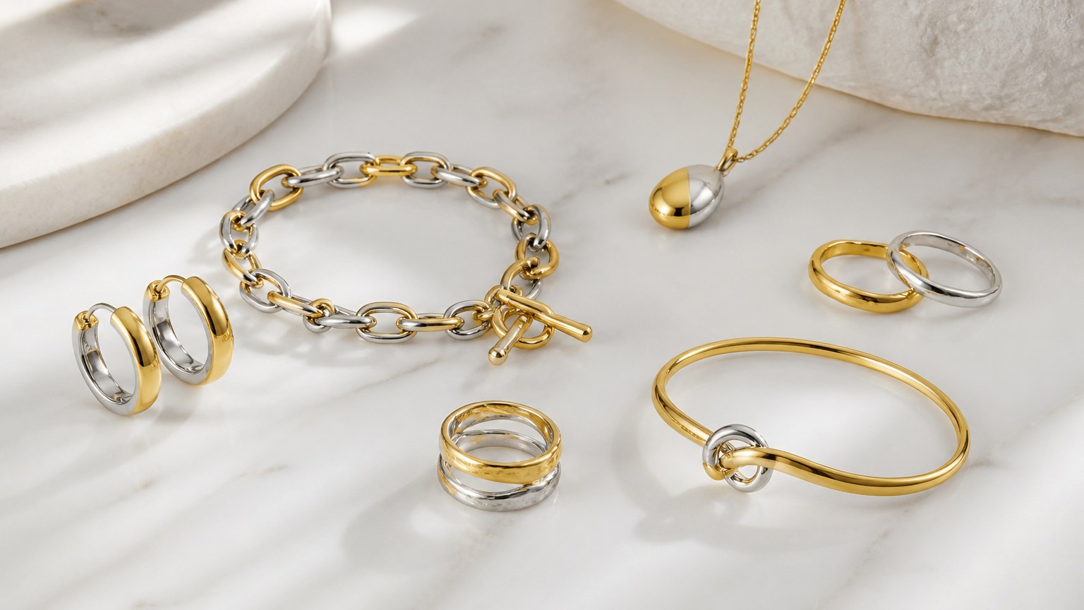 Pièces de bijoux argent massif recouvertes d’or en style vermeil posées sur marbre blanc